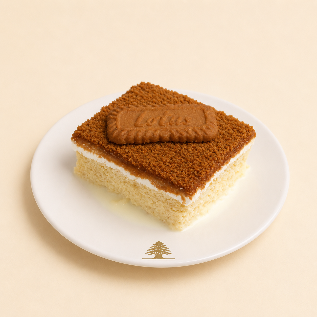Slice of Biscoff milk cake topped with cookie crumbs and a whole Lotus biscuit